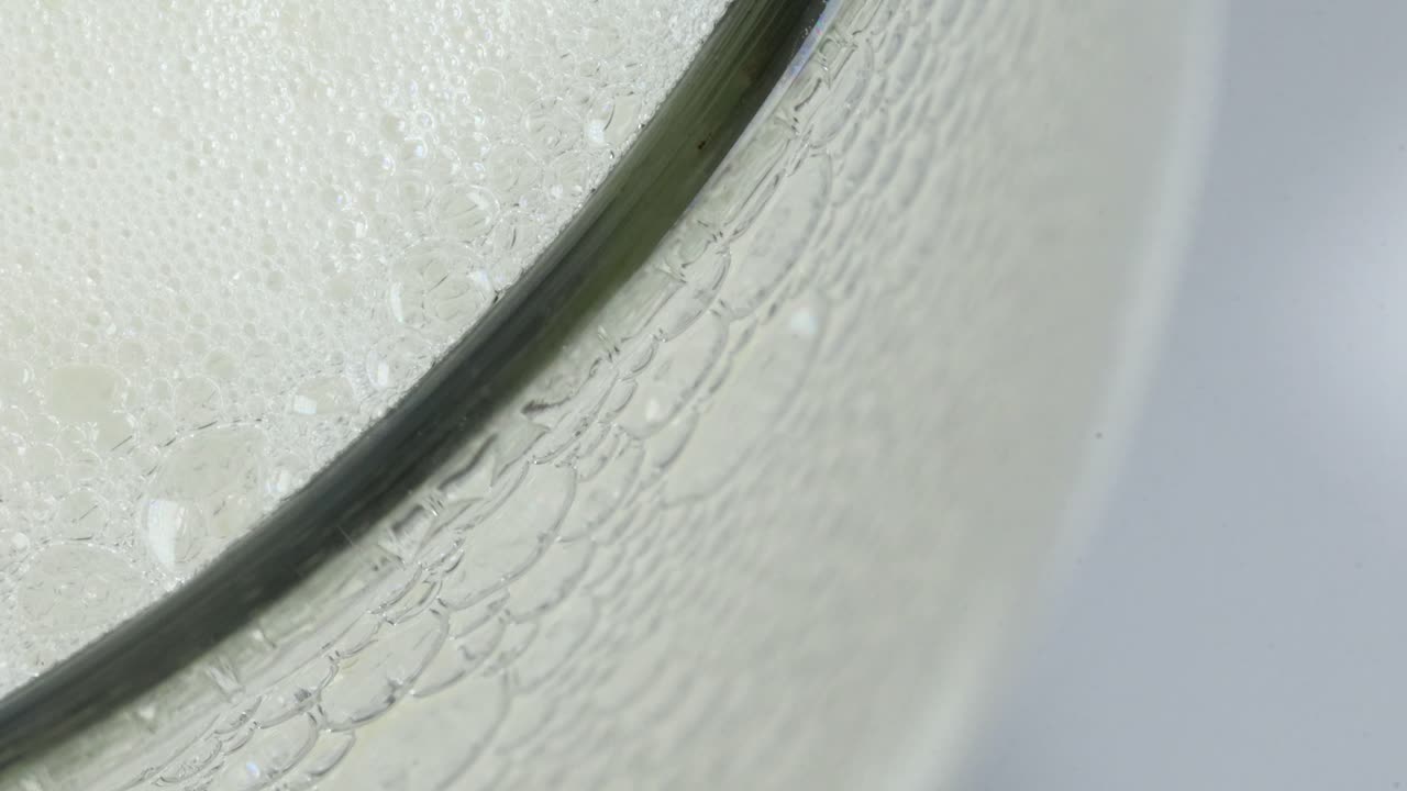 투명한 유리병에서 많은 거품이 자라고 반응하고 폭발합니다.