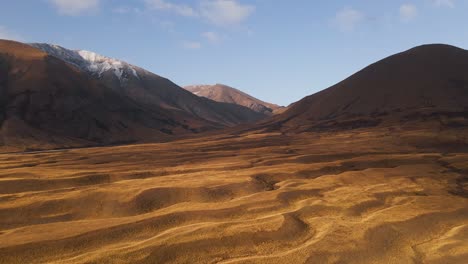 Schöne-Wellenförmige-Goldene-Ebenen-Mit-Bergketten-Im-Hintergrund