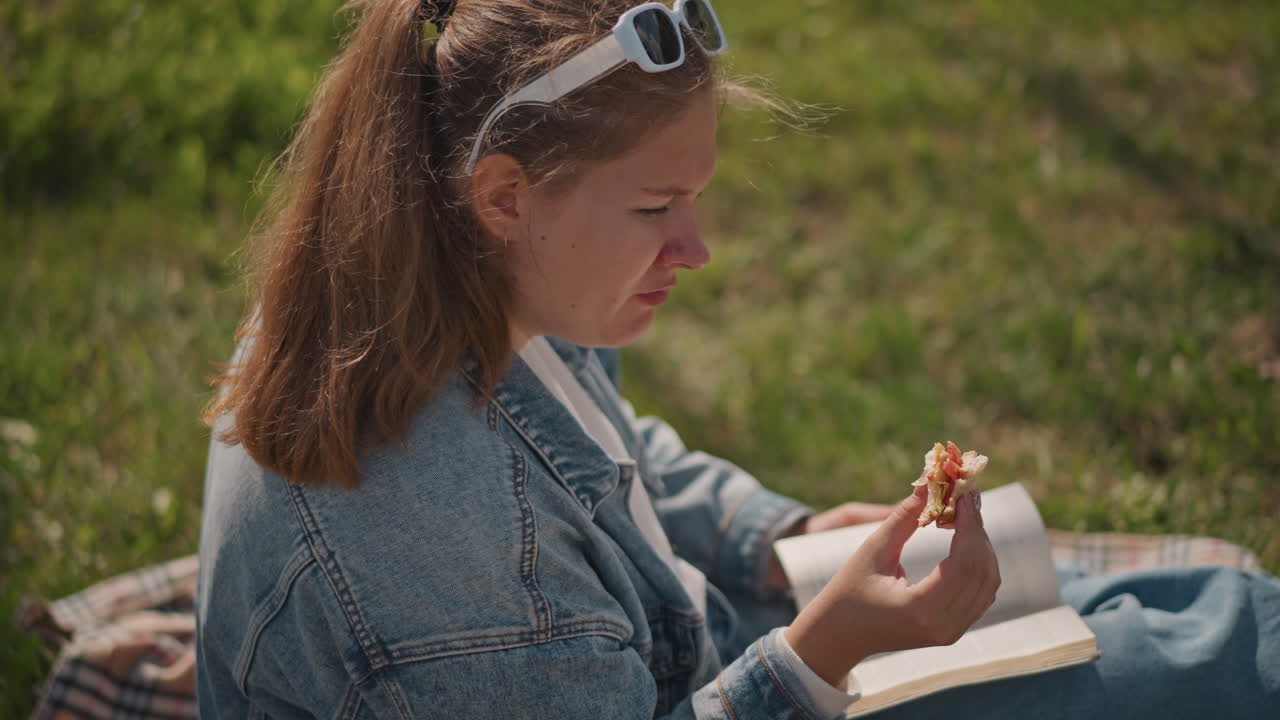 Lettura tranquilla al parco. Uno studente studia con calma all'aperto oggi. Individuo rilassato che si gode un momento di pace con un libro all'esterno. Momento sereno di studio e relax su una coperta da parco sull'erba assolata.