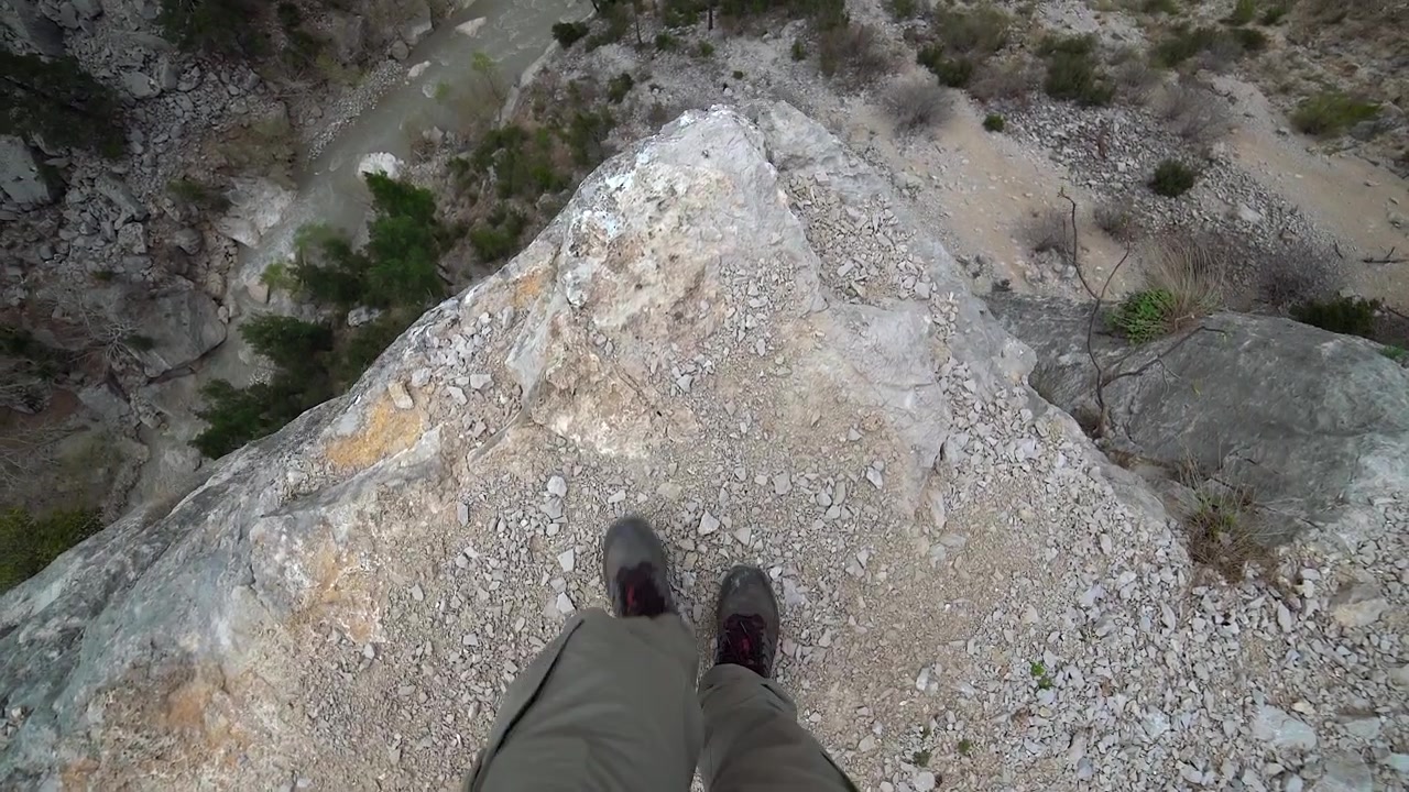 Hiker Standing on the Edge of a Steep Rocky Cliff