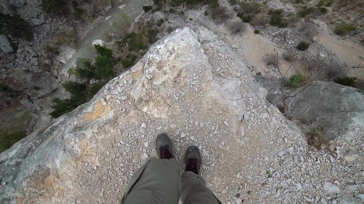 Hiker Standing on the Edge of a Steep Rocky Cliff
