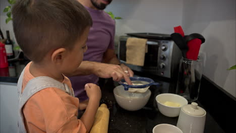 joven niño latino mexicano ayudando a su padre en la cocina mientras hacen galletas usando un tamiz para la harina