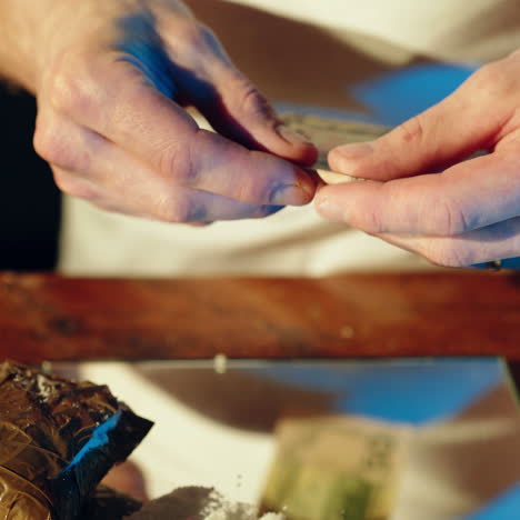 abuse of drugs. young addict's man sniffs and snorts a line of cocaine with a roll of banknote on the mirror. square video