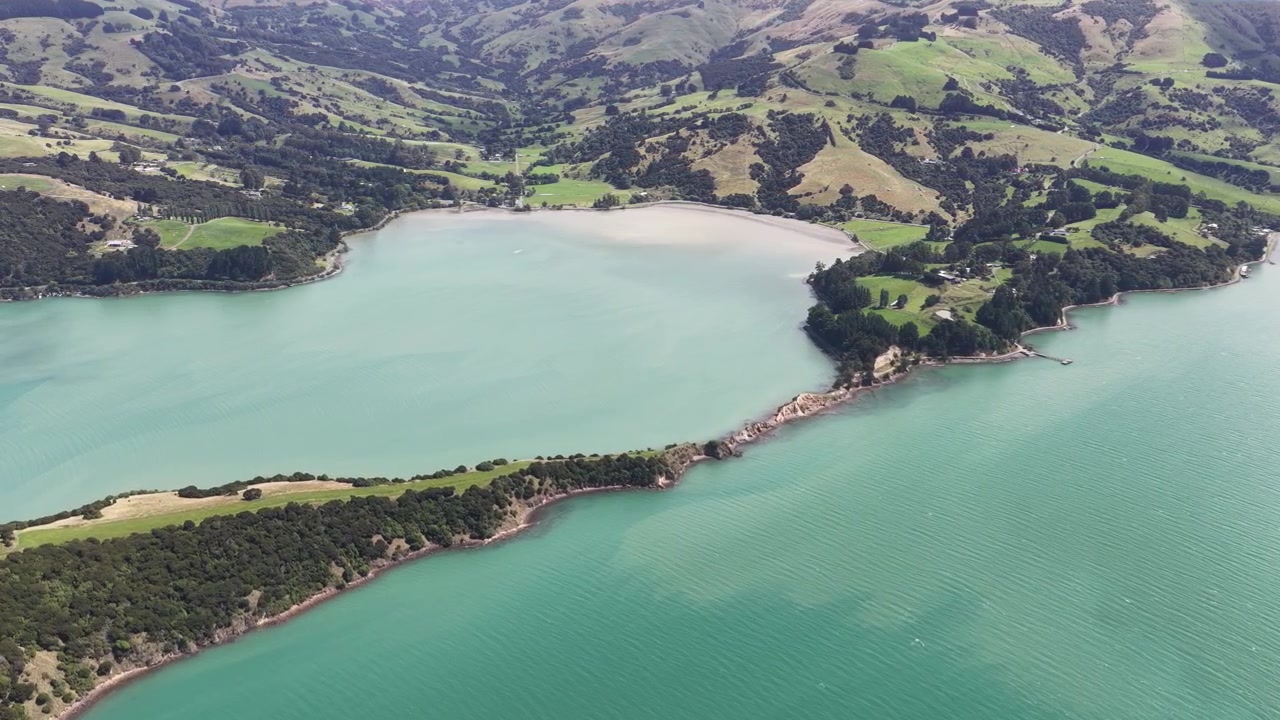 Panorama aereo di acque costiere turchesi e strette formazioni peninsulari lungo l'Isola del Sud della Nuova Zelanda, che rivela baie panoramiche, la costa e tranquilli paesaggi marini.