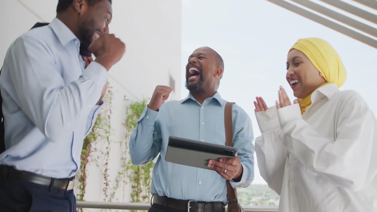 Happy diverse business people celebrating and using tablet at office, slow motion