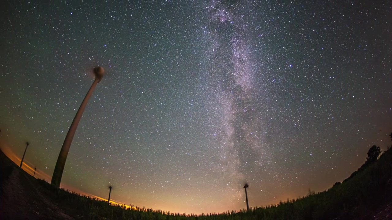 Timelapse da Via Láctea, turbinas eólicas, estrelas cadentes, chuva de meteoros, galáxia girando, da noite para o dia.