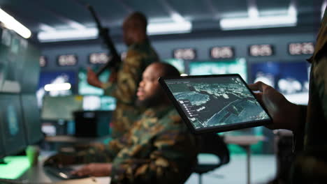 Military-agent-working-in-control-room,-using-software-on-tablet