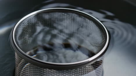 metal mesh strainer submerged in water
