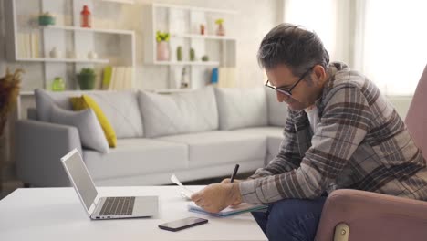 Man-looking-at-bills-doing-calculations-with-calculator-at-home.