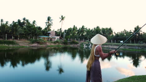 mulher atraente com chapéu cônico pescando no lago tropical do vietnã, vista de órbita