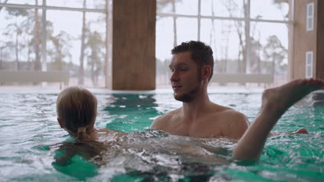 Un-Hombre-Adulto-Está-Enseñando-A-Su-Hija-En-Edad-Preescolar-A-Nadar-Bañándose-Juntos-En-Un-Entrenamiento-De-Natación-En-Piscina