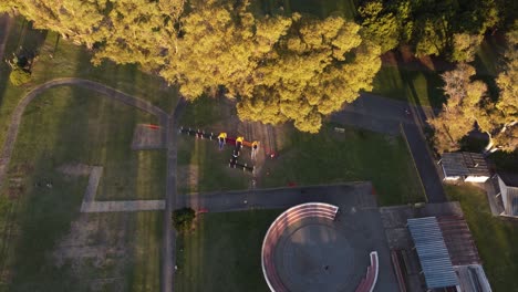 Ariel-view-of-a-group-of-Kids-playing-together-during-a-sunny-day-at-park-which-is-surrounded-by-trees