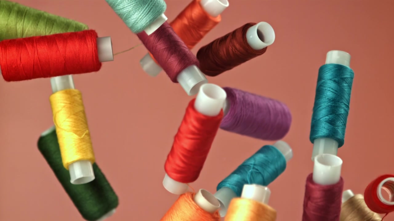 Colorful Sewing Thread Spools Falling in Slow Motion