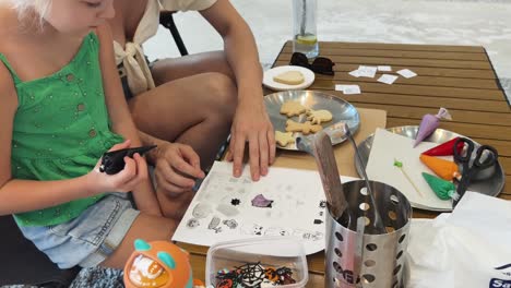 mother and daughter decorating halloween cookies