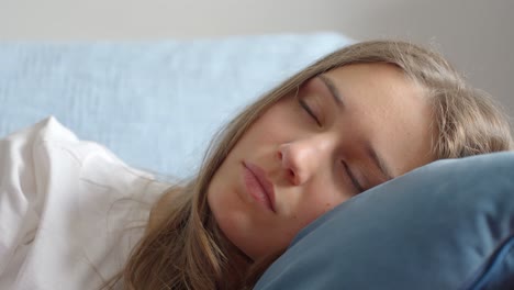 Close-up-of-a-young-brunette-woman-putting-her-head-on-the-pillow-and-going-to-sleep