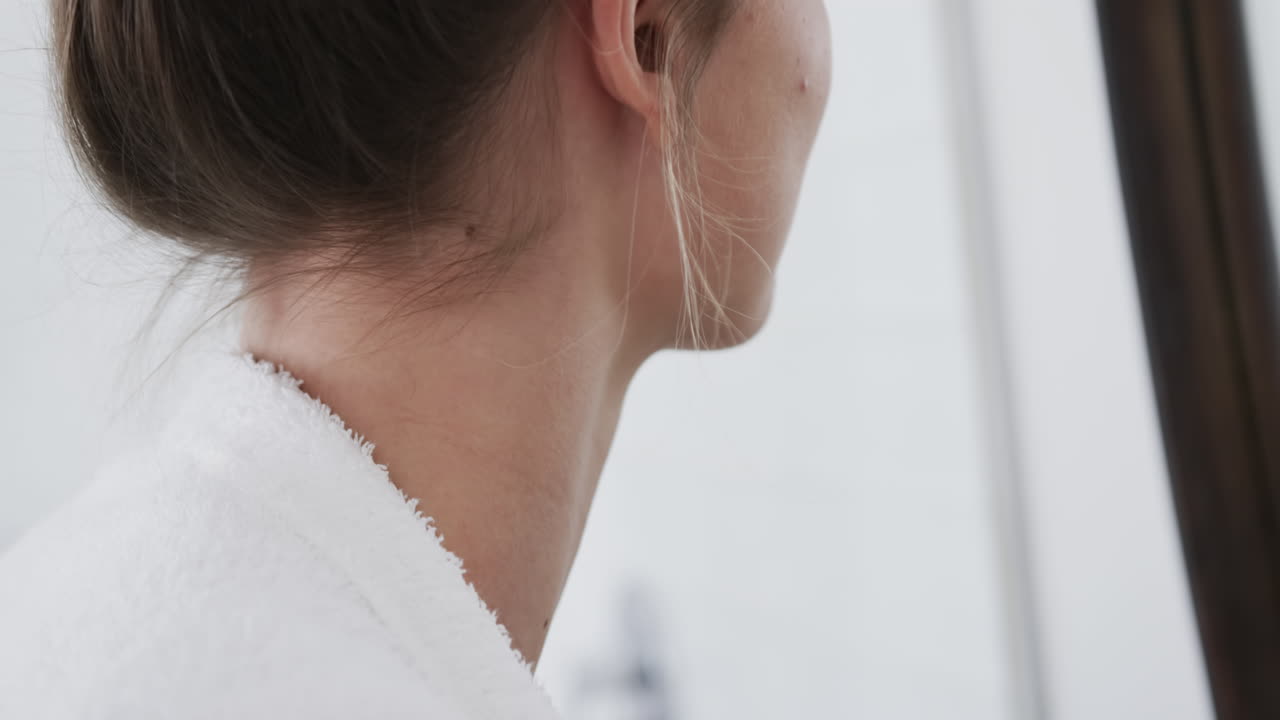 mujer biracial tocando su cara mirándose en el espejo en el baño, cámara lenta