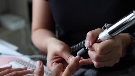 maestro anónimo de pulido de uñas de una cliente femenina con una lima eléctrica
