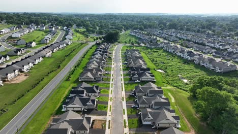new developed residential area with upper class houses and villas. well-kept suburb district of american town with similar buildings along street. descend drone wide shot. tranquil drone wide shot