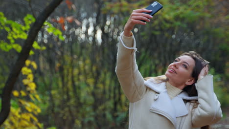 mujer tomando una selfie en un parque de otoño