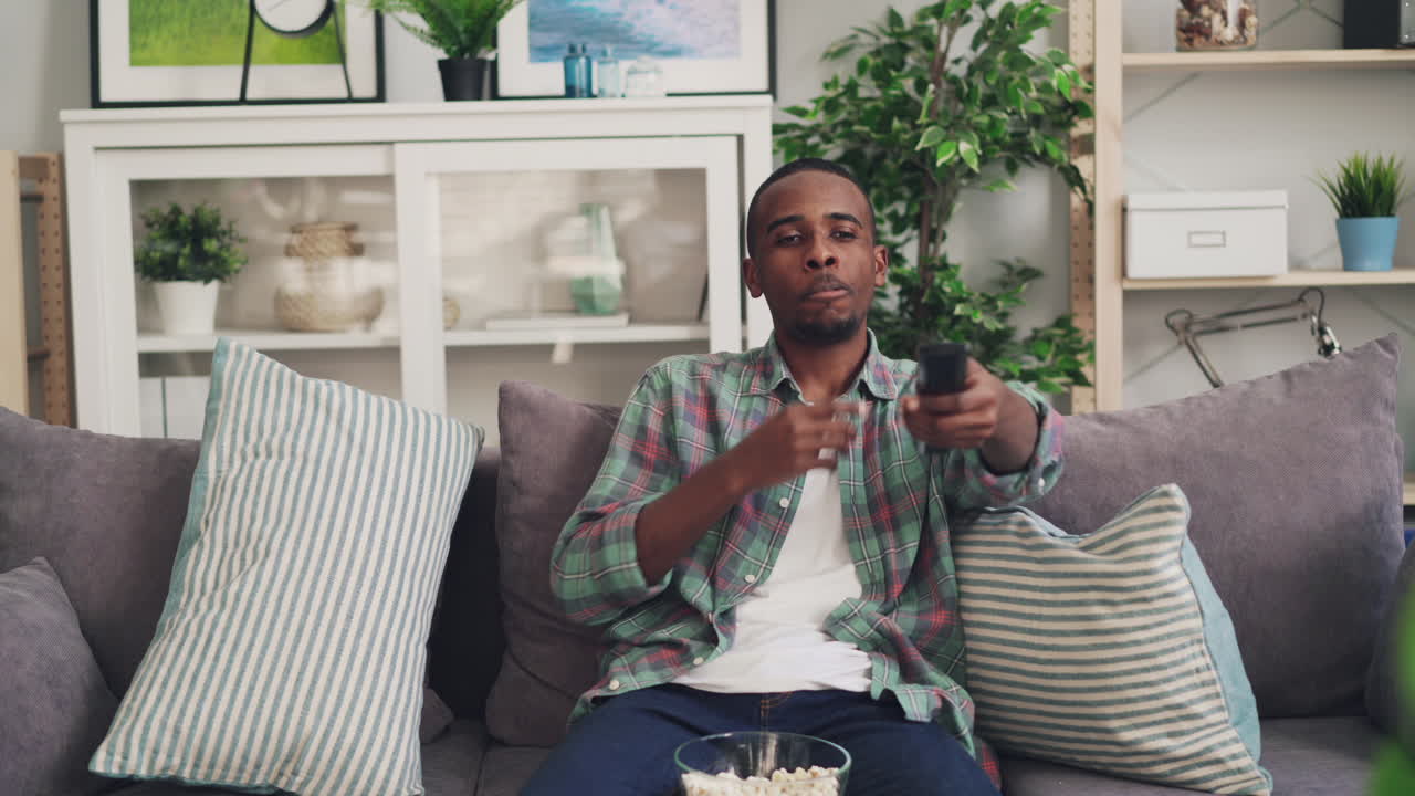 Mand ser tv på sofaen med popcorn