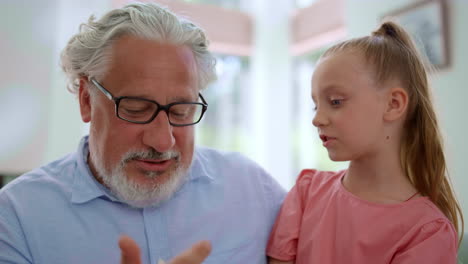niña sentada en las rodillas del abuelo. abuelo enseñando a la nieta a contar