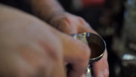 pouring liquor into measure glass to prepare cocktail in nightclub, close up