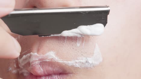 man shaving his mustache with foam and a razor