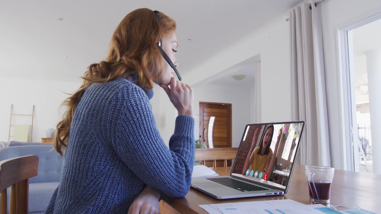 mujer caucásica con auriculares de teléfono haciendo una videollamada con una colega en una computadora portátil en casa