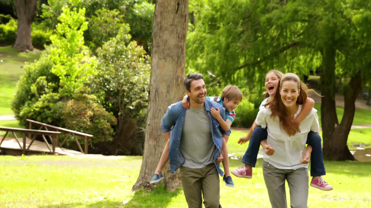 familia feliz jugando persiguiendo en el parque juntos