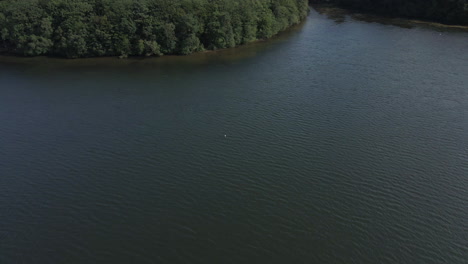 Aerial-drone-ascending-pov-over-Trémelin-or-Tremelin-over-lake-and-beautiful-green-forest,-Brittany-in-France