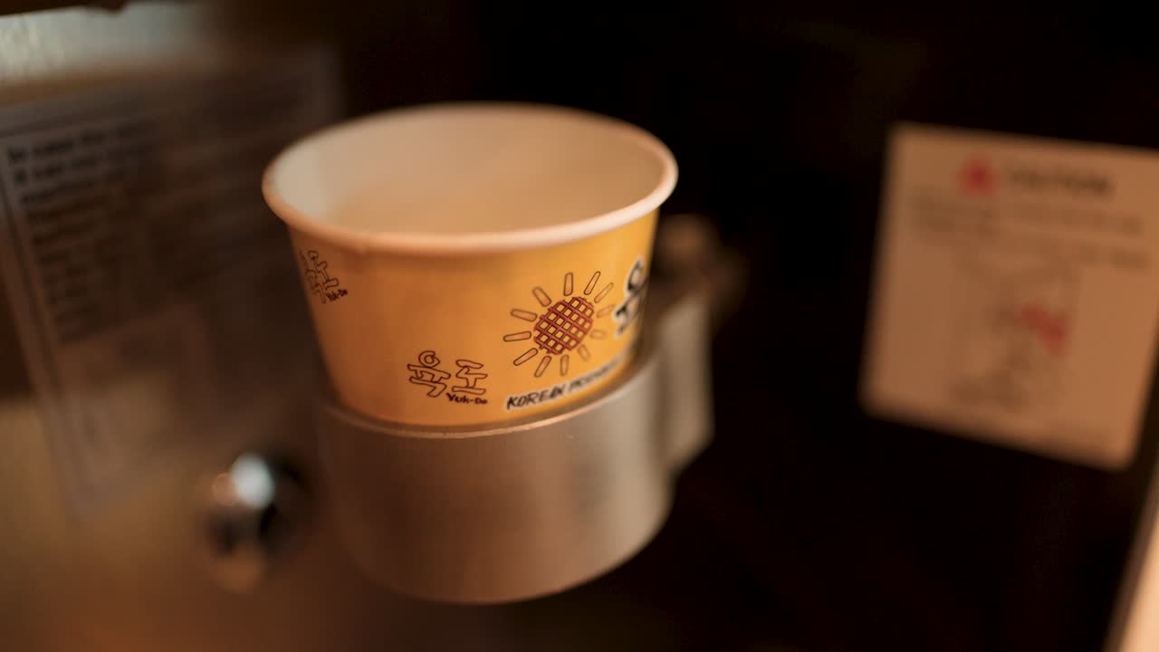 Primo piano di una macchina automatizzata che versa un gelato soft serv bianco in una coppetta