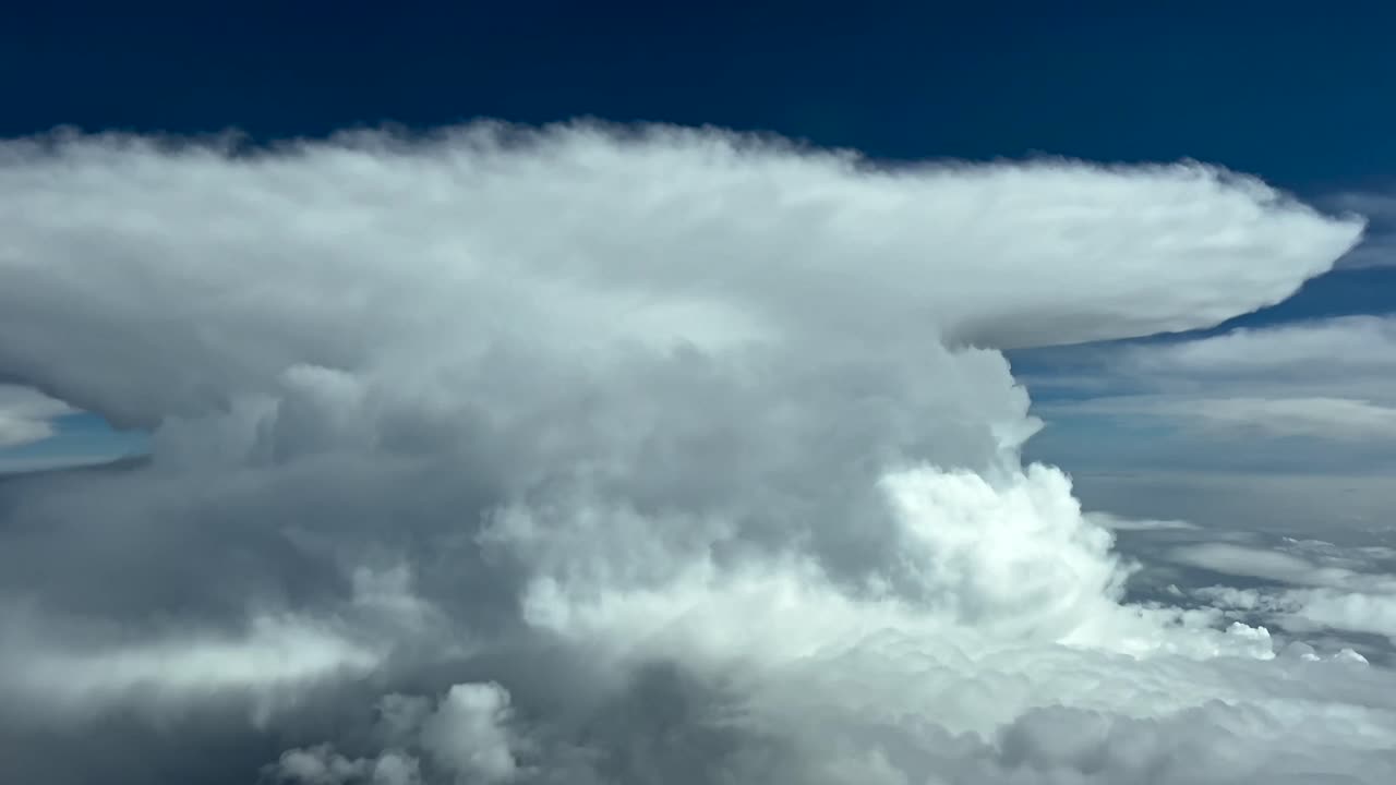 Pilot POV flying in a stormy sky with a massive cumulonimbus storm cloud ahead with its perfect anvil shape. Immersive view from cockpit. 4K