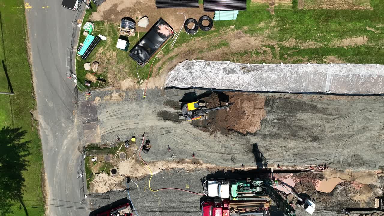 drone de arriba hacia abajo subiendo por encima de la excavadora y la sombra en el campo de trabajo de hierba