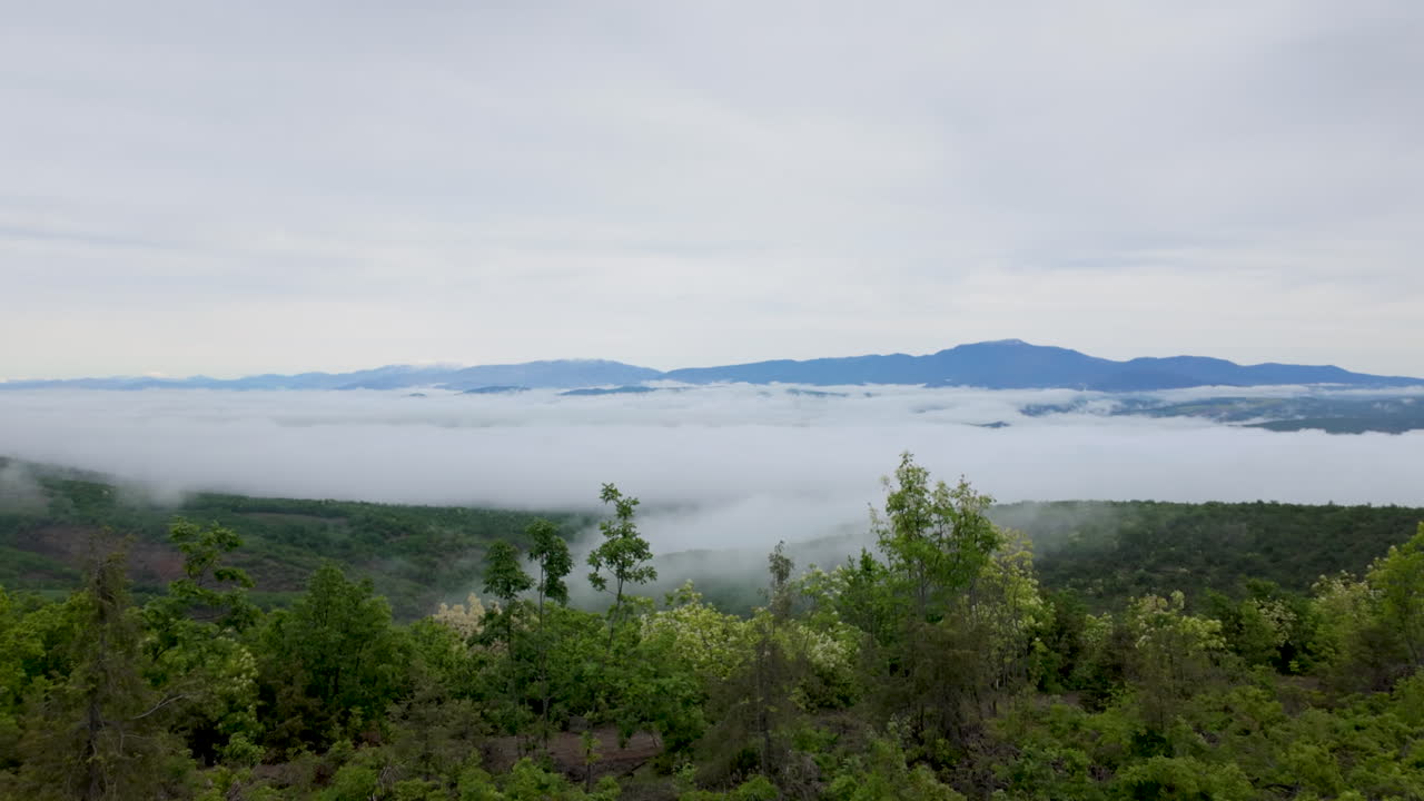 A serene cinematic shot of a Greek mountain valley filled with thick white fog and low clouds at dawn. Perfect for travel documentaries and nature backgrounds