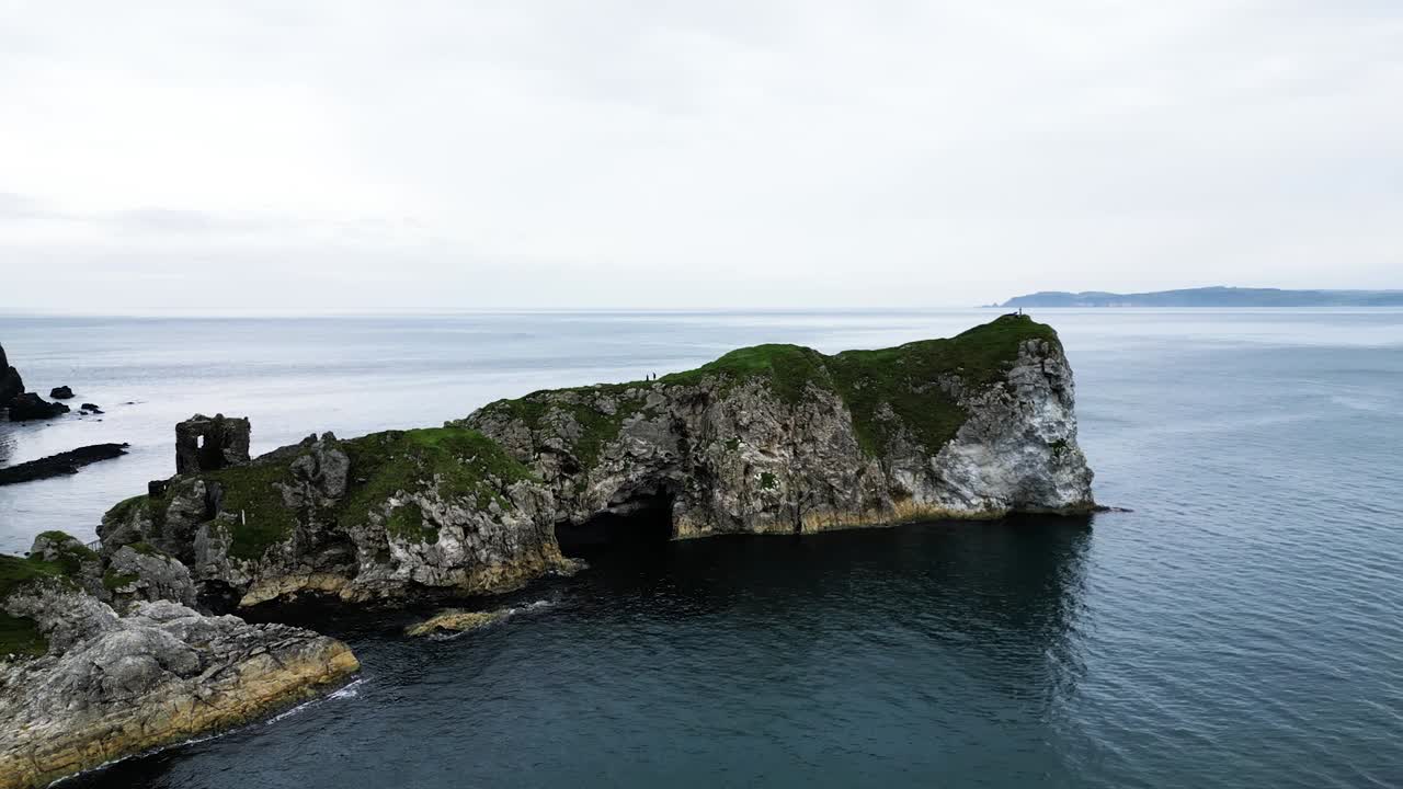 vista aérea del majestuoso castillo de kibane en irlanda del norte, tomada a lo largo de la poderosa calzada costera con vistas al mar tranquilo, las rocas y una isla en el fondo durante una expedición