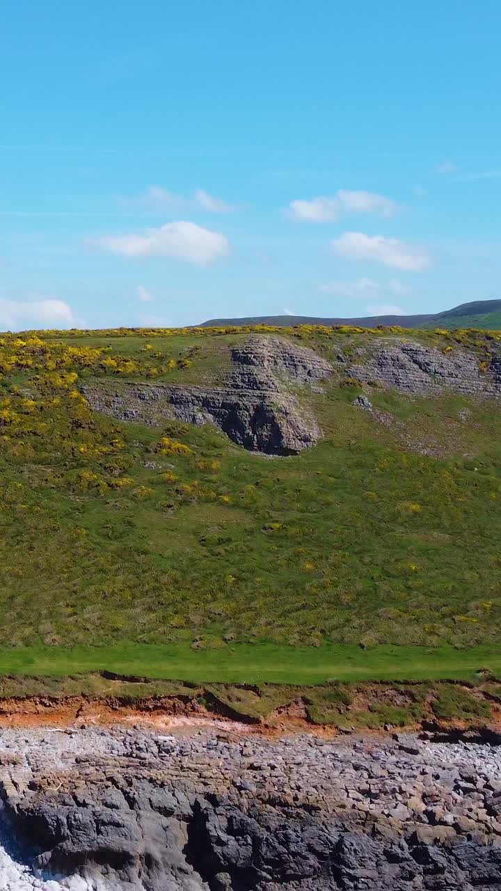 Vertical Video Rising Drone View of Cliffs Revealing Large Rhossili Bay Beach with Big Mountain and Sand Dunes in Background.