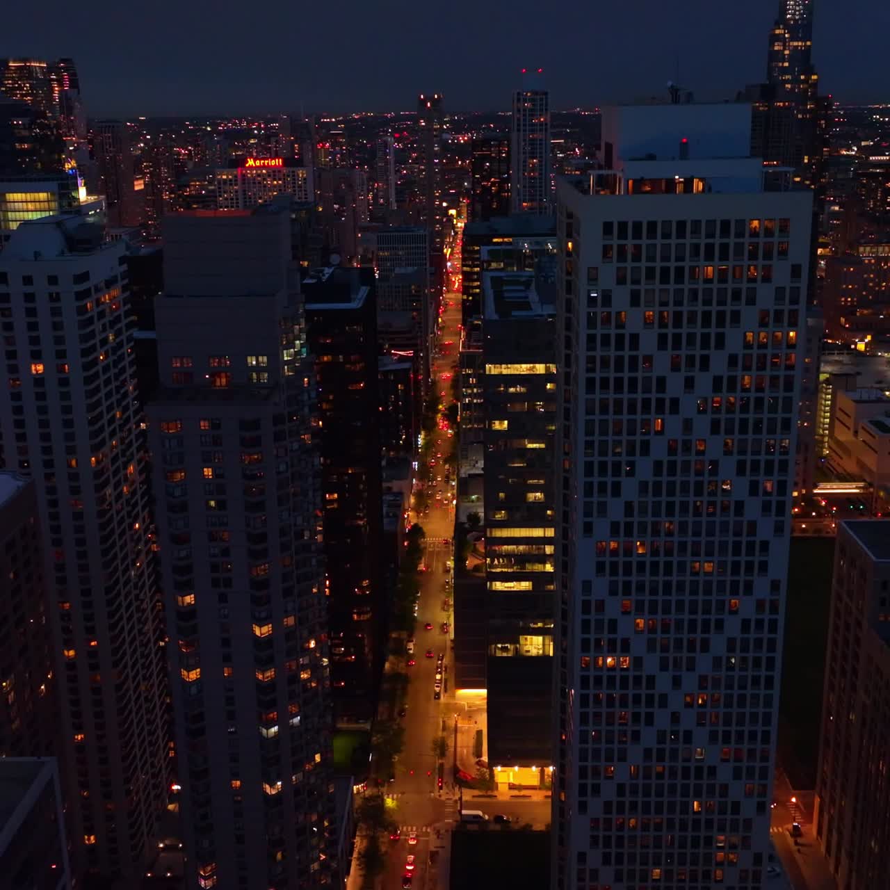 Bright street with many cars going between modern skyscrapers. Drone footage rising from the tops of wonderful buildings