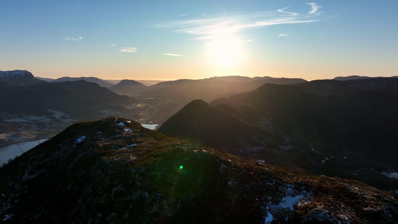 Slow orbit around person on mountaintop in Vindafjord and Olen, capturing sunset and sun flare