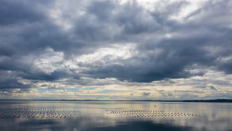 aerial time lapse of the clouds moving above a still ocean, reflection of clouds in the water