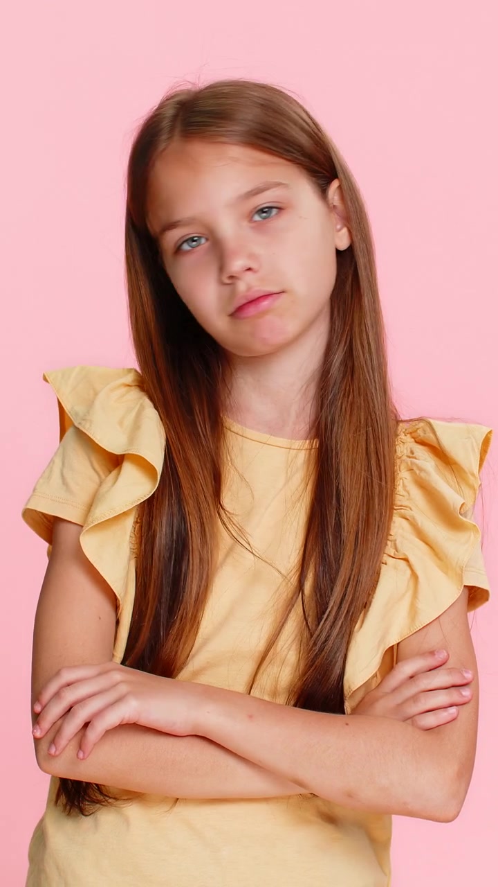 Bambina che mostra il gesto del pollice verso con il broncio, esprimendo disapprovazione o un senso di fallimento.