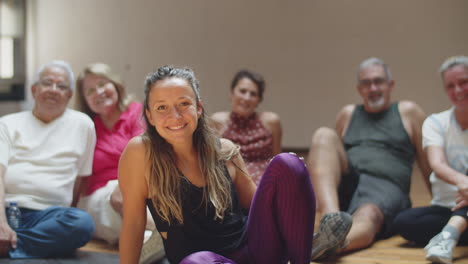 Long-shot-of-female-teacher-sitting-with-dancing-group-on-floor