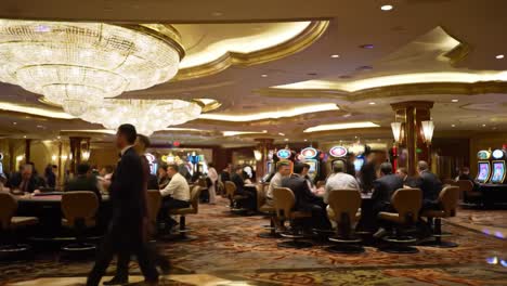 an elegant casino experience: a bustling environment filled with gamblers and slot machines underneath stunning crystal chandelier lighting