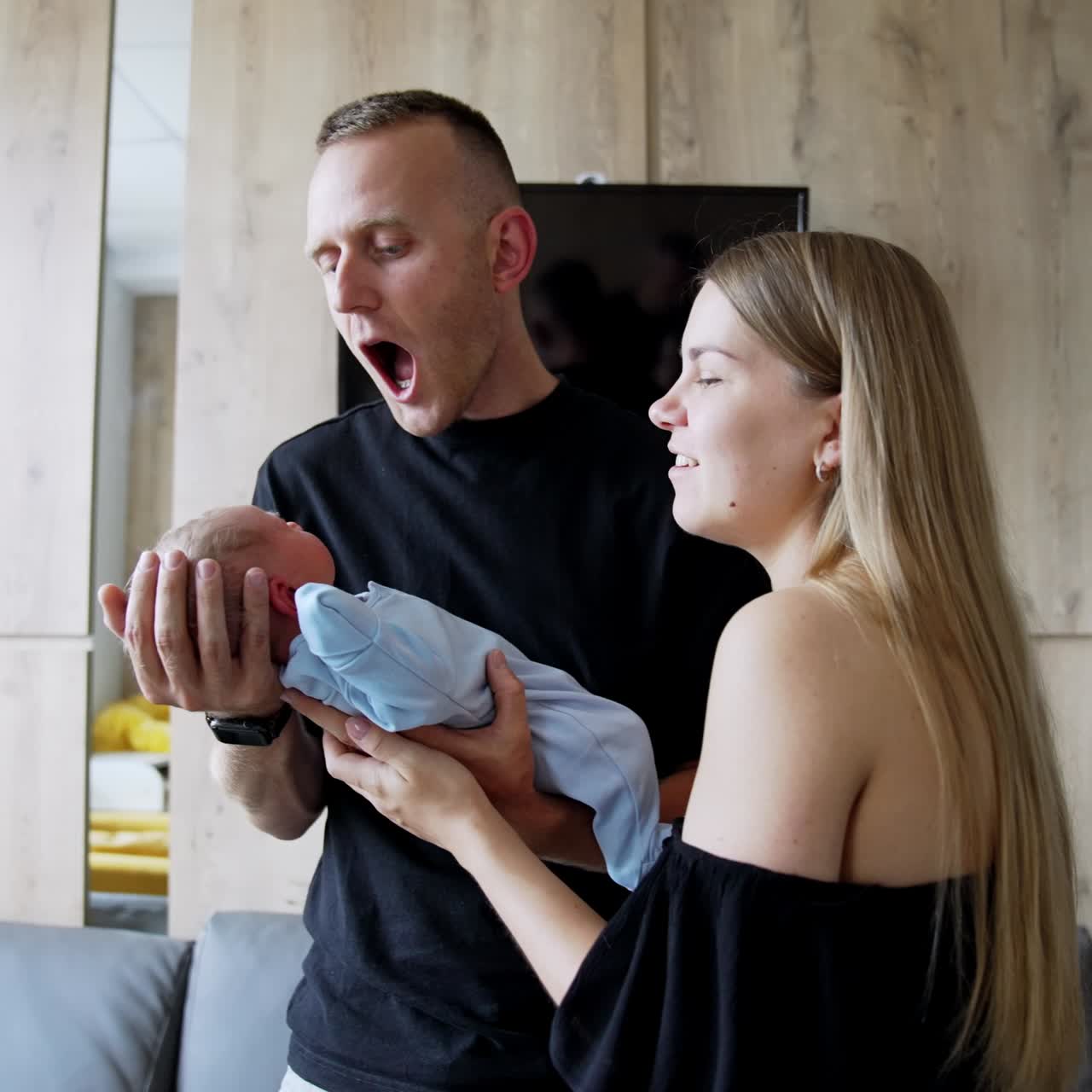 Caucasian parents hold their newborn son. Caring couple talking and smiling to their little kid