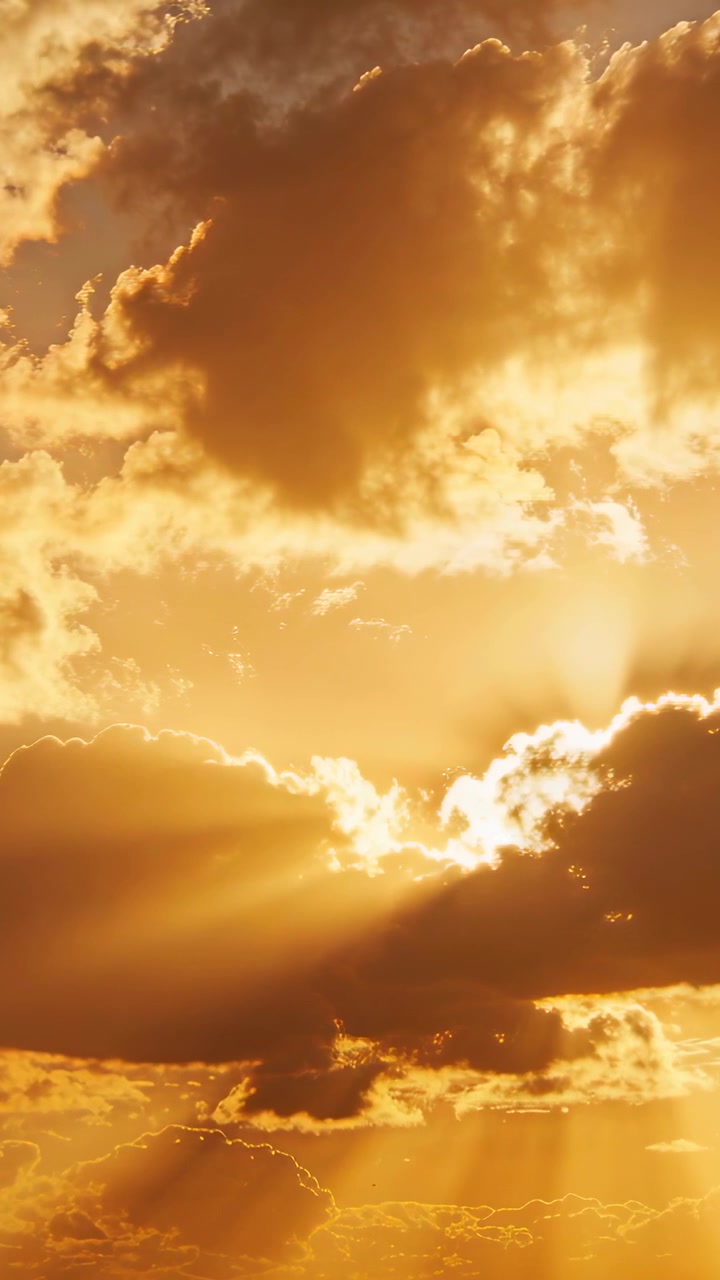 Vertikal video: En skiftende cumulussky åbner et hul, solen bryder igennem og sender stråler på en gylden himmel.