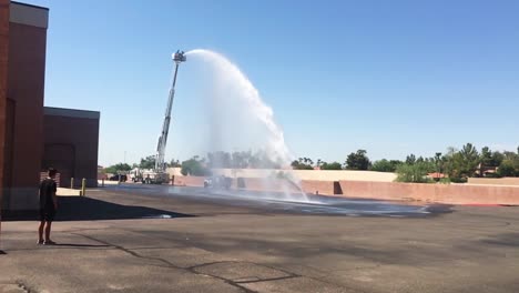 en el espectador saluda a los bomberos locales mientras el agua rociada de la manguera en la parte superior del camión con escalera