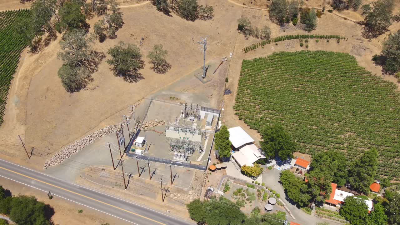 una pequeña estación de transmisión de energía o subestación de distribución en una zona rural de california cerca de viñedos y colinas - vista aérea