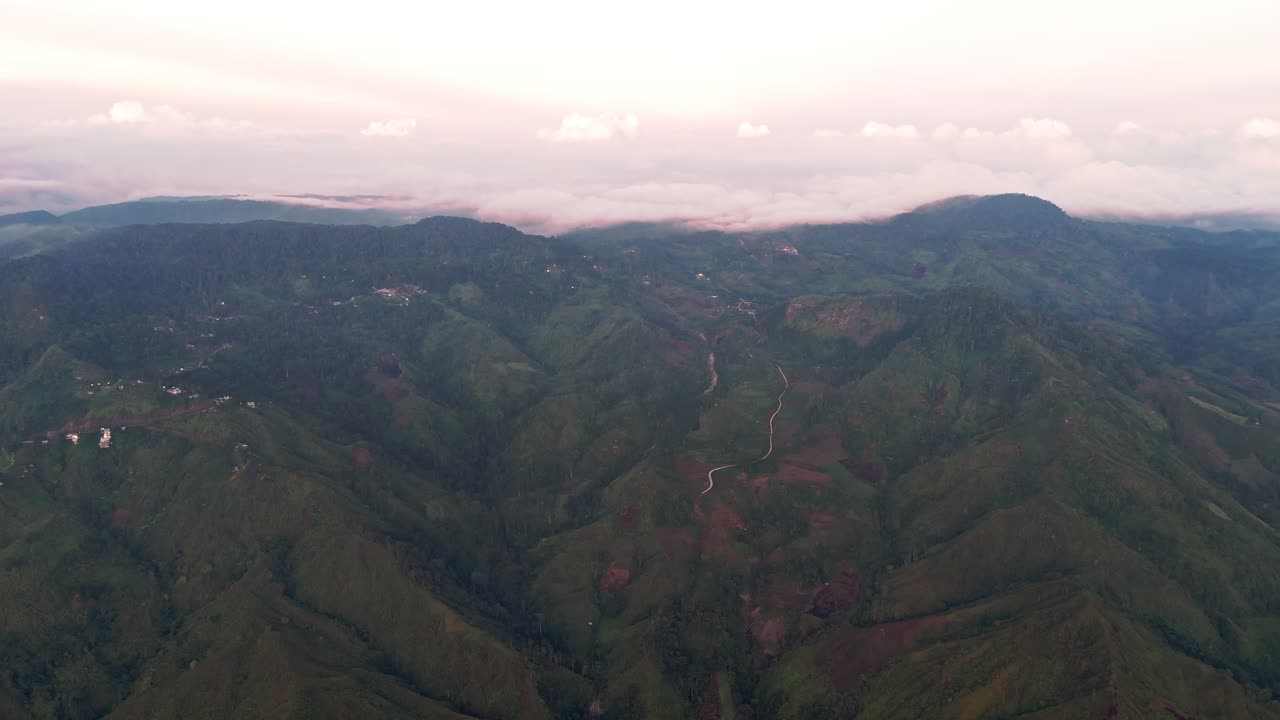 Cinematic drone shot of lush green mountains, winding roads, and cloud cover. Perfect for travel, tourism, documentaries, and cinematic storytelling