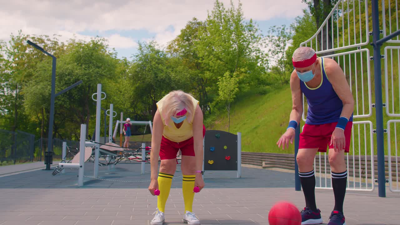 코로나 바이러스 전염병 기간 동안 스포츠 놀이터 코트에서 농구를 하는 활동적인 시니어 남자 여자