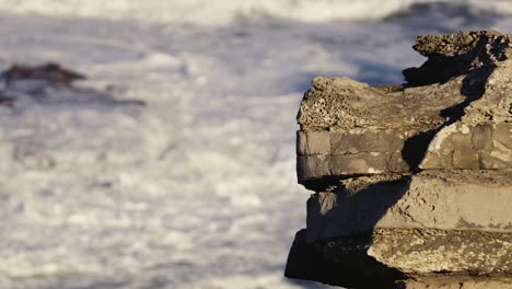 eroded stones and rough ocean waves in background, portugal coast near peniche