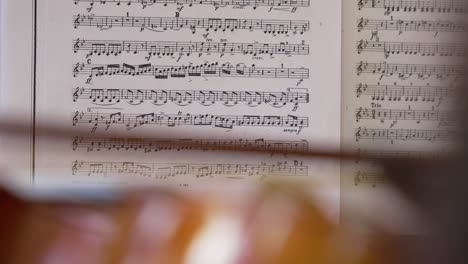Close-Up-of-a-Violin-Focused-with-a-Sheet-of-Musical-Notes-in-the-Background